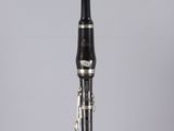 a close up of a black and silver clarinet on a clear surface