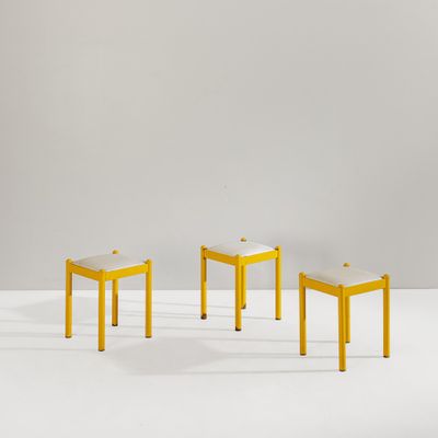 three yellow stools sitting on top of a white surface