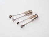 three silver spoons sitting on top of a white surface