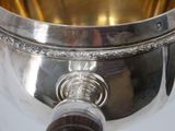 a silver bowl with a wooden handle on a white table