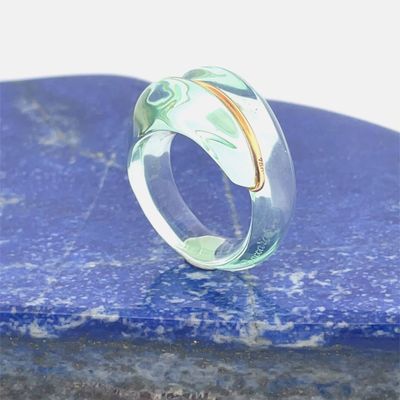une bague transparente ornée d'un anneau en or serti d'une pierre bleue