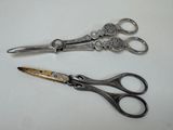 two pairs of scissors sitting on a white surface
