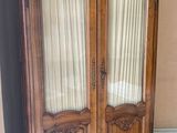 a wooden armoire with two doors and a rug on the floor