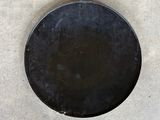 a black plate with a hole in it sitting on a cement floor