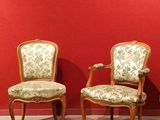 pair of antique chairs against a red wall in a room