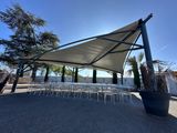an outdoor dining area with tables and chairs under a canopy