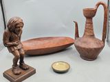 a statue of a man sitting next to a bowl and a vase