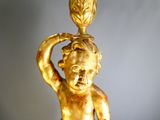 a gold statue of a boy holding a pot on his head
