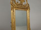 an ornate gold framed mirror with a bird and flower decoration