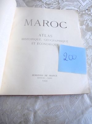 un livre ouvert, sur lequel est collé un autocollant, posé sur un lit