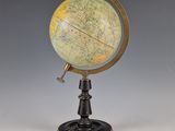 un vieux globe terrestre posé sur un socle, avec une clé à l'intérieur
