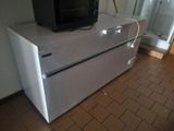 a television sitting on top of a refrigerator in a room