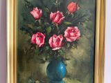 un tableau représentant des roses roses dans un vase bleu posé sur une table