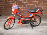 a small red motorcycle parked in front of a brick wall