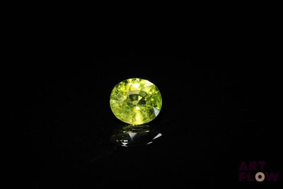 a green gemstone in the dark on a black surface