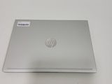 the back of a silver laptop sitting on top of a white table