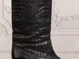 a pair of black cowboy boots sitting on top of a wooden table