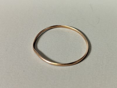 gros plan d'une bague en or sur une surface blanche