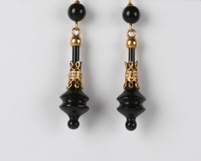 une paire de boucles d'oreilles noires et dorées sur fond blanc