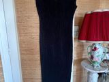 a black dress hanging on a wooden hanger in a room