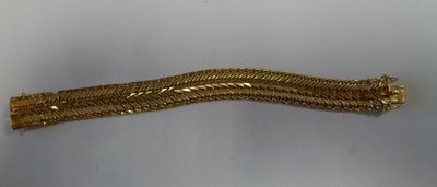 gros plan d'un bracelet en or sur une surface blanche