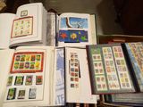 de nombreux timbres posés sur une table, à côté d'un livre ouvert