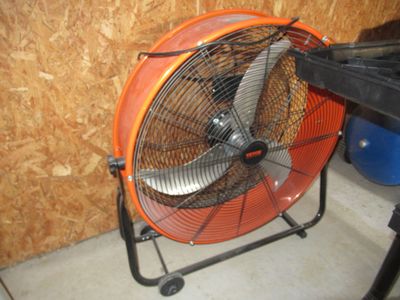 un ventilateur posé par terre à côté d'une table