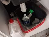 a trash can under a sink with a plastic container underneath it