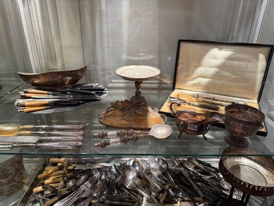 a glass display case filled with silverware and other items