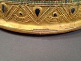 an image of a gold crown with blue and green stones on it