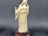 a statue of a monk on a wooden base with a black background