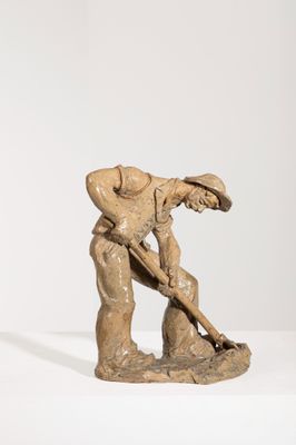 sculpture représentant un homme tenant une pelle, posée sur une surface blanche