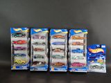 Six petites voitures Hot Wheels sont alignées en rang sur une table