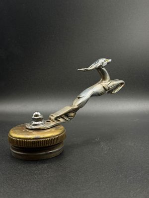 une image représentant un oiseau argenté posé sur un objet métallique
