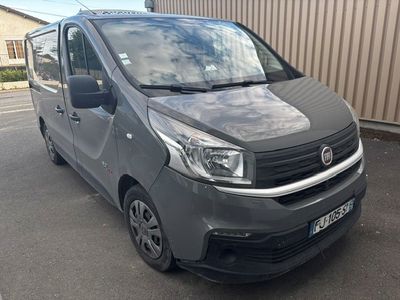 La camionnette grise est garée sur le parking près d'un immeuble.
