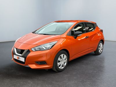 La voiture orange est garée dans une pièce au sol noir.
