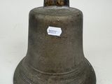 a metal bell with a sticker on it on a white surface