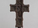 une vieille croix en bronze posée sur un socle noir, sur fond blanc