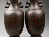 pair of antique chinese bronze vases on pedestals against a gray background