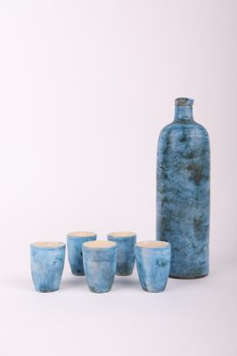 cinq tasses et une bouteille posées sur une table