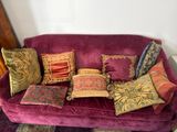 a purple couch with many pillows on it in a room