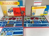 three boxes of meccano are sitting on a white surface