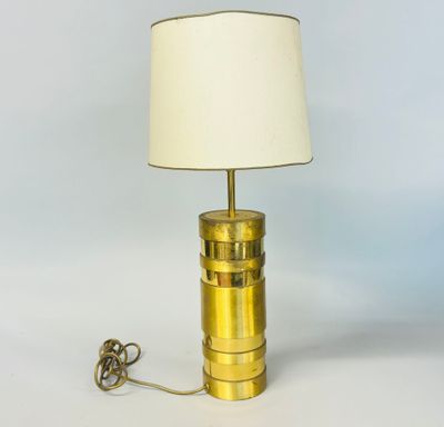 a brass table lamp with a white shade on top of it