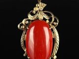 a gold and red stone pendant on a black background