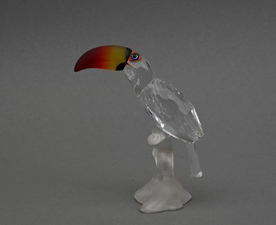 une figurine en verre représentant un toucao perché sur une branche