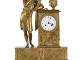 une horloge en or sur laquelle est représentée une femme tenant un vase