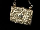 a silver purse on a chain on a black background