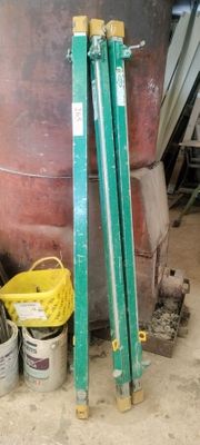 a large metal container with a green handle next to buckets of paint