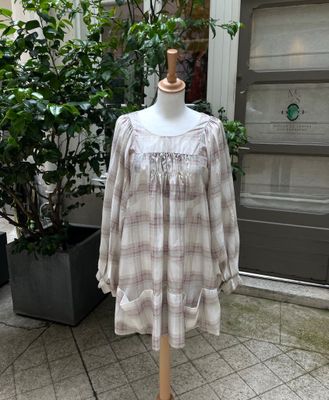 une robe à carreaux beiges et blancs posée sur un mannequin devant un immeuble
