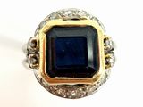 gros plan d'une bague avec une pierre bleue entourée de diamants